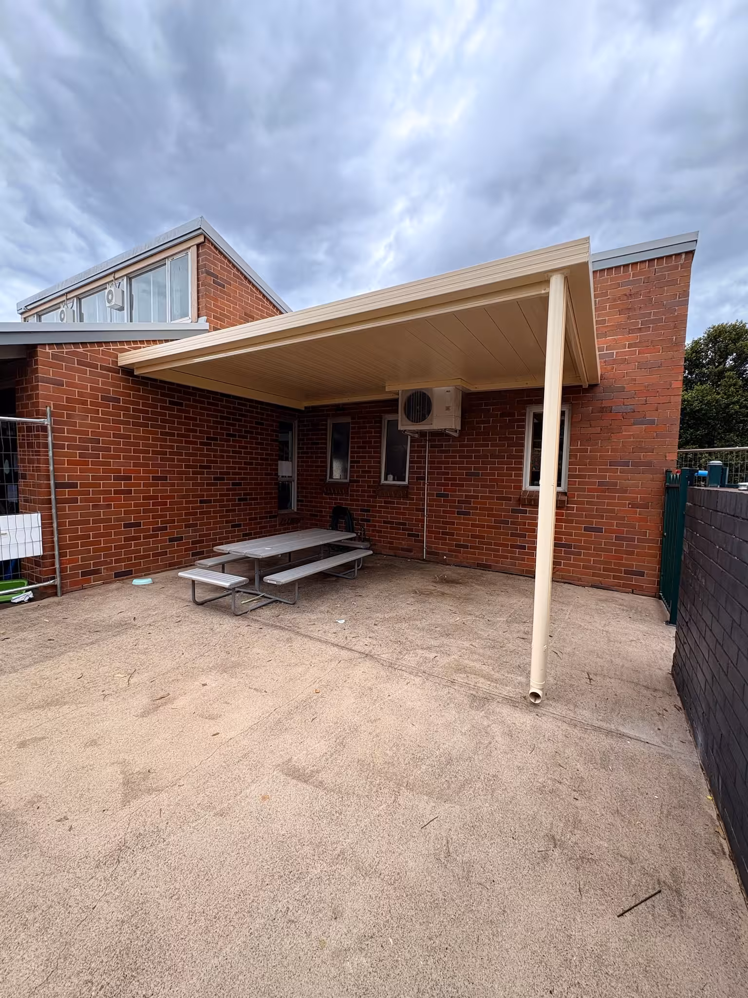 Pergolas & Carports project — Cream Colorbond patio cover attached to a brick home